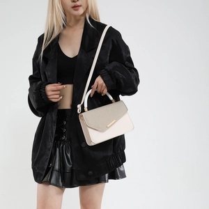 Elegant two-tone cream and beige square handbag with a gold bar clasp on a model