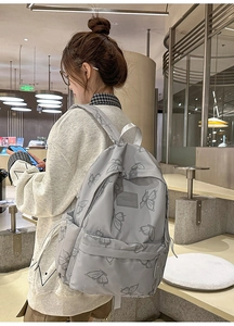 Detail of light grey butterfly print backpack in a casual setting on a female model