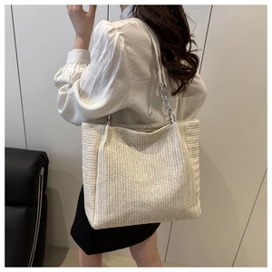 Detail of cream woven tote bag featuring stylish silver metal chain strap and knit texture