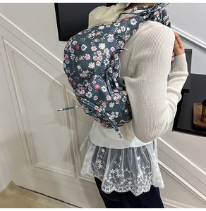 Detail of floral crossbody dumpling bag with pink and white patterns on dark blue fabric