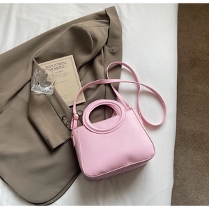 Detail view of pink minimalist handbag with circular handle on a stylish background