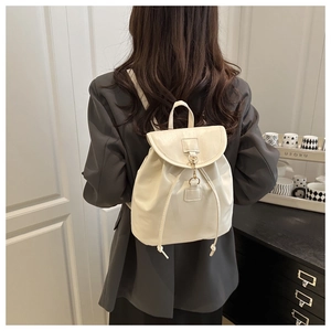 Rear view of a model wearing a cream leather backpack with gold ring hardware