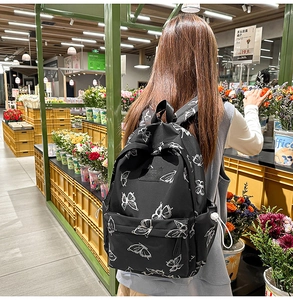 Close-up of lightweight black butterfly print backpack with large zip pocket for travel