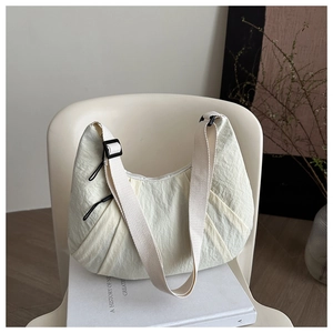 Close-up of beige pleated fabric texture and adjustable wide strap of the dumpling bag