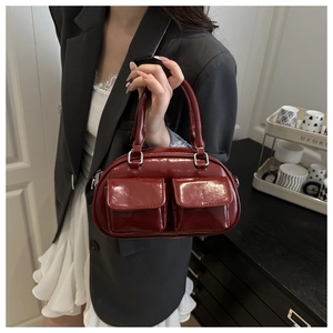 Detail view of burgundy glossy shoulder bag with dual front flap pockets and silver hardware