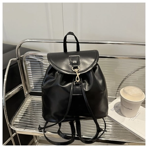 Close-up of black PU leather backpack with metallic hook closure on a silver bench