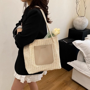 Minimalist beige woven straw tote bag with brown leather pocket and white rope handles
