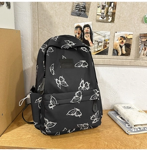 Close-up of black backpack with white butterfly pattern and durable front zipper pocket