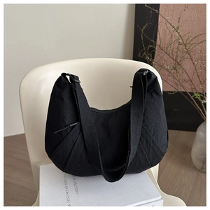 Detailed close-up of the black nylon crescent bag featuring unique accordion pleats on the base