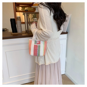 Detail of colorful striped woven tote bag with silver snap button and white handles