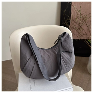 Detail of grey lightweight nylon crescent bag with adjustable strap on creative chair