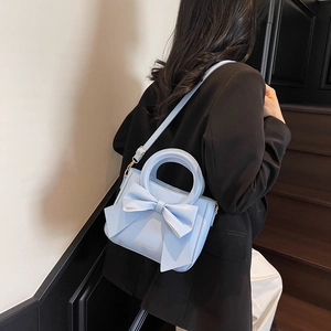 Elegant light blue handbag with oversized bow detail and round hollow top handle