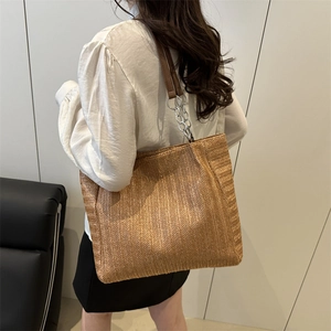 Large capacity straw tote bag with brown woven pattern and metal chain strap on model