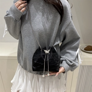 Black satin drawstring bucket bag with silver butterfly metal trim and chain strap