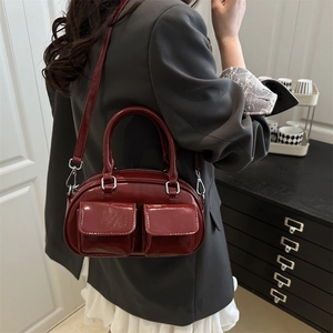 Deep red patent leather baguette bag with dual front pockets and silver buckles