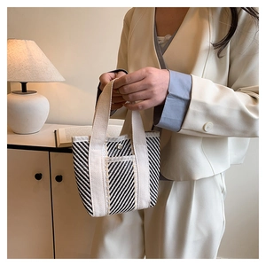 Detail of handwoven black and white striped tote bag with beige canvas handles and metal buckle