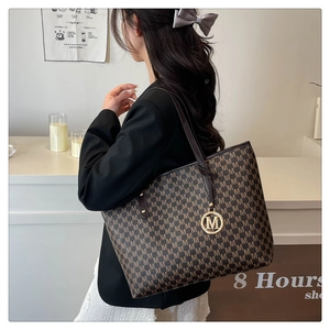 Detail of large tote bag with M-letter jacquard pattern and gold metallic charm