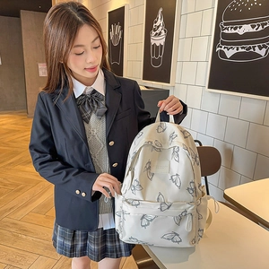 White butterfly print nylon backpack for students shown on a model in a cafe setting