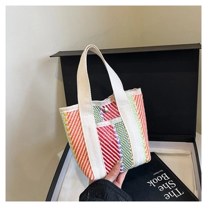 Detail view of the colorful woven tote bag showing canvas handles and metallic snap button