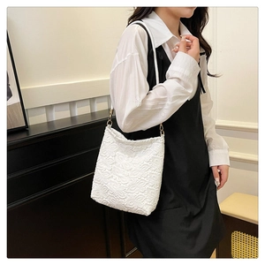 Close-up of white floral lace shoulder bag with elegant gold metal hook and strap
