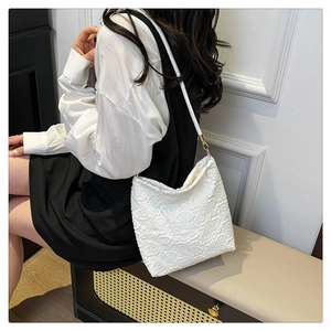 Detail of floral lace texture and leather strap on this cream white tote shoulder bag