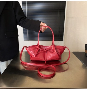 Detail of red pleated woven handbag with iconic bow accent and matte leather finish