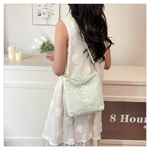 Detail showing white lace floral embroidery and light green texture on the tote bag