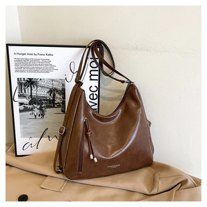 Detail view of coffee brown faux leather hobo bag with tassel and vertical zipper pocket