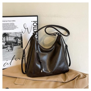 Close-up of dark brown leather tote bag with vertical zipper and tassel detail