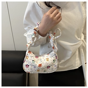 Détail du sac croissant blanc avec imprimés cartoon colorés et bandoulière froncée chic