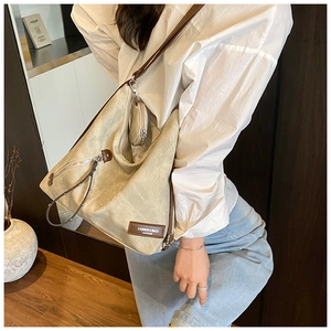 Detail view of beige large-capacity tote bag with brown leather strap and small round pouch