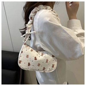 Détail du sac croissant blanc avec imprimés d'ours et bandoulière plissée avec nœud