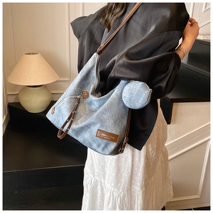 Detailed macro of washed blue denim tote bag with leather strap and coin purse accessory