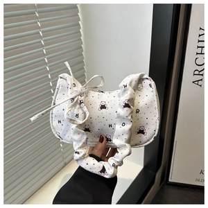 Détail du sac à bandoulière en toile blanche avec imprimés d'ours et bandoulière plissée