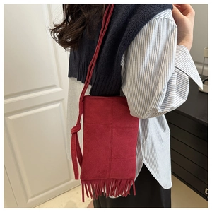 Detail of red suede crossbody bag with fringe tassels shown on model for size