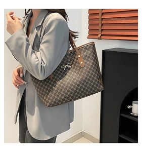 Grand sac cabas tendance en toile monogramme marron porté avec un blazer gris décontracté