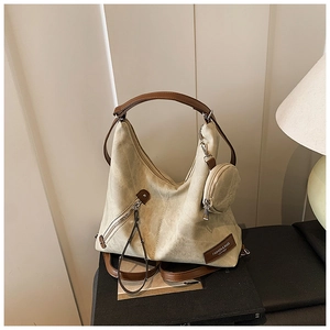 Detail view of large tote bag with contrast brown straps and small round coin purse charm