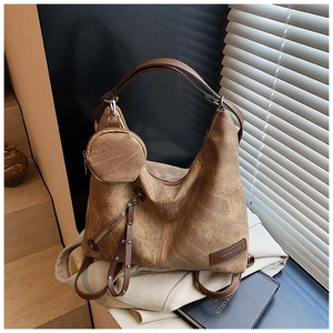 Detail view of brown vintage frosted leather tote bag with round hanging pouch and side zipper