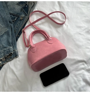Pink mini shell bag with a black smartphone showing compact size and matte leather texture