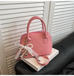 Detail of pink seashell bag with pearl heart charm and elegant lace ribbon detail