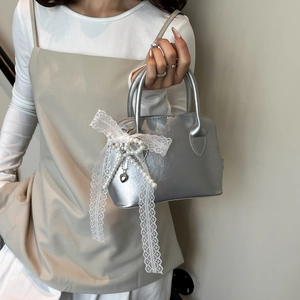 Silver shell Boston bag with white lace bow and pearl charm accents for elegant style