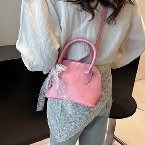 Pink shell handbag with lace and pearl charm shown on model for a trendy spring style