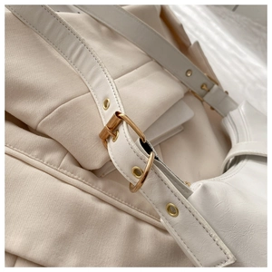 Close-up of cream white tote bag strap with gold metal buckle and leather texture