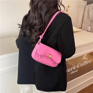 Minimalist bright pink PU leather shoulder bag with gold clasp shown on model in cafe