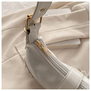 Detail of white patent leather shoulder bag with golden zipper and metal rivet accents