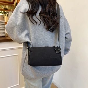 Black high-capacity multilayer crossbody bag with unique round zipper pulls on model