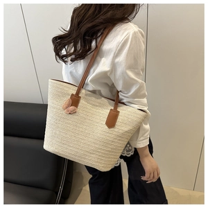 Straw tote bag detail with beige woven texture, brown leather handles, and pink butterfly