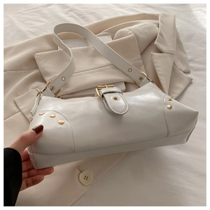 Close-up of white leather shoulder bag featuring gold buckle and metal rivet details