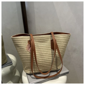 Detailed view of handmade straw tote bag with brown leather straps and pink butterfly charm
