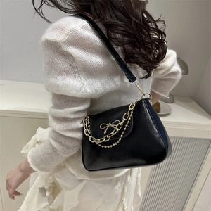 Elegante borsa sottobraccio nera con fiocco dorato e catena, vista su modella